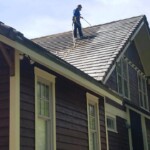 AAA Contractor Services cleans roofs! Man on an roof pressure washing shingles